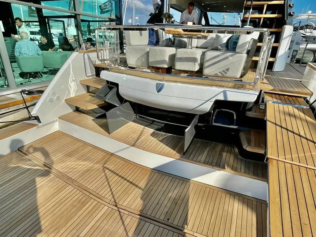 Luxury yacht interior with stylish furnishings, wooden decking, and crew member visible at the helm.